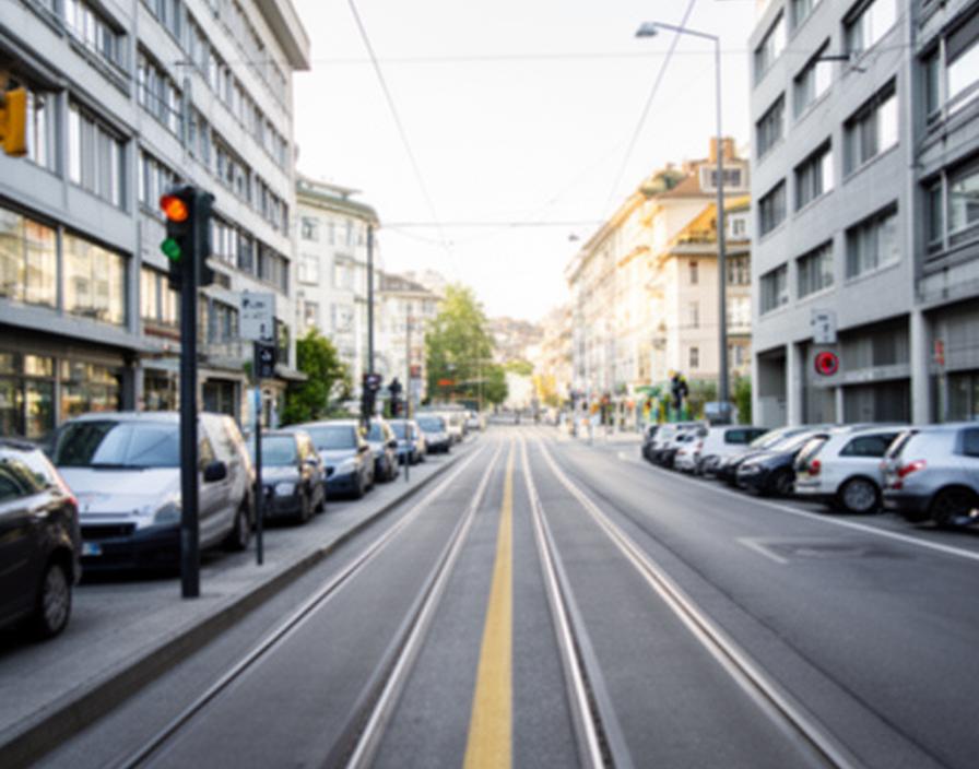 Strassenbild nahe Zürich Oerlikon mit Tramspur, Stadtgebäude und Parkmöglichkeiten an einem hellen Vormittag